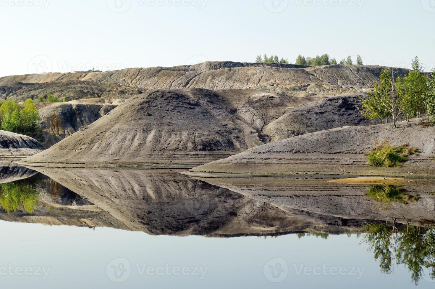 vista em uma pedreira inundada com reflexo de colinas e árvores. foto