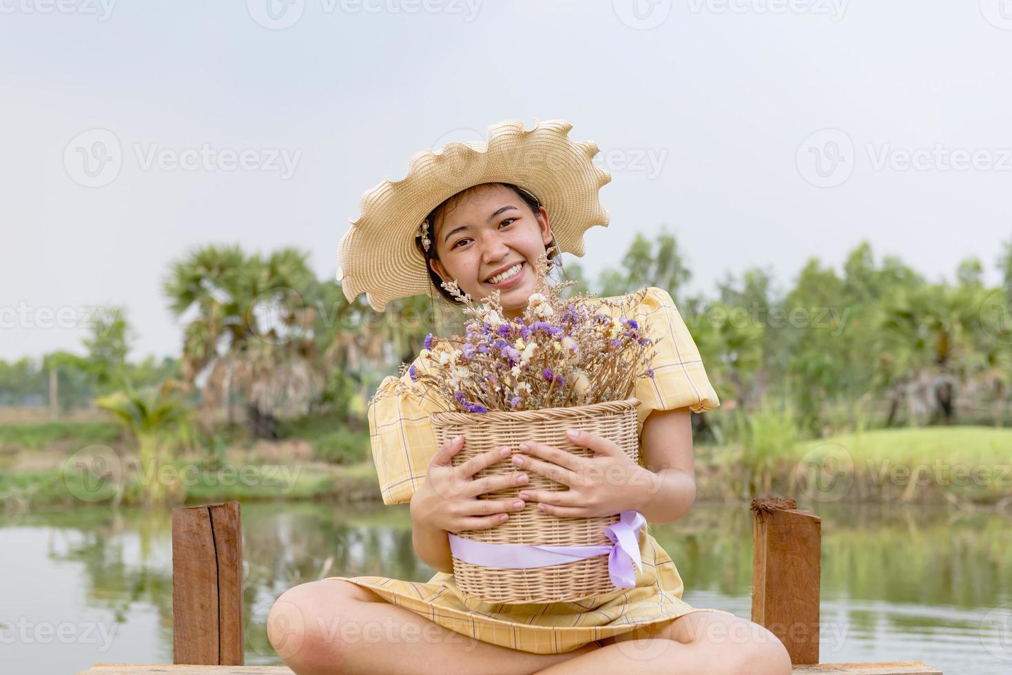 felicidade, uma linda mulher no jardim, colocada em um chapéu, segurando flores. foto