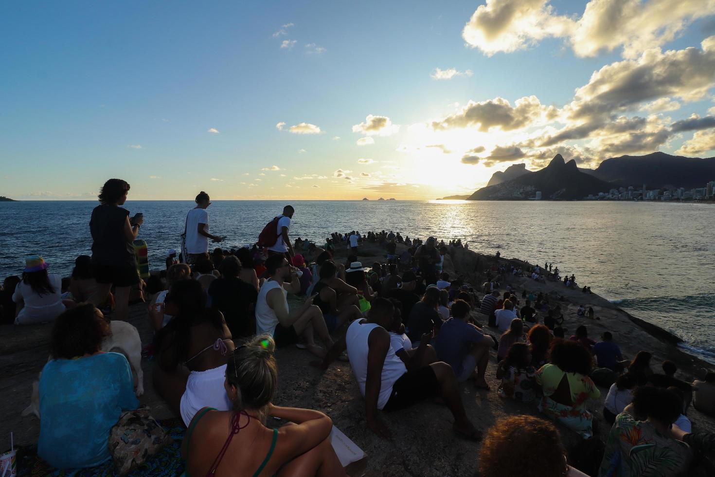 rio de janeiro, rj, brasil, 2022 - pessoas em silhueta assistem o pôr do sol na rocha do arpoador, praia de ipanema foto