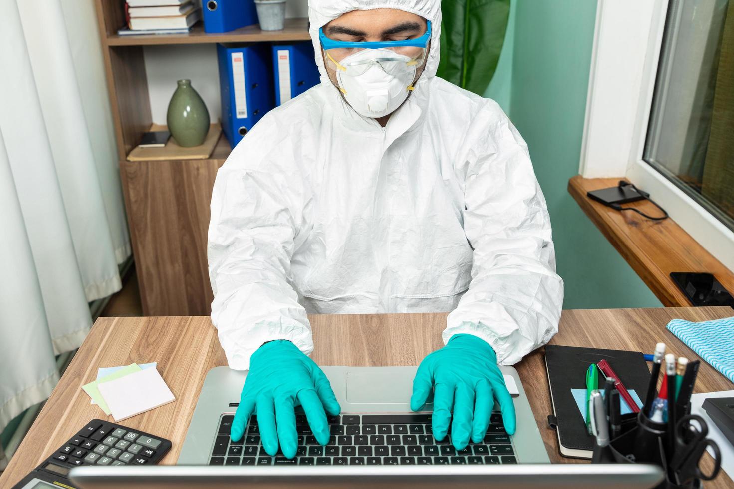 homem com roupa de proteção pessoal trabalhando no computador foto