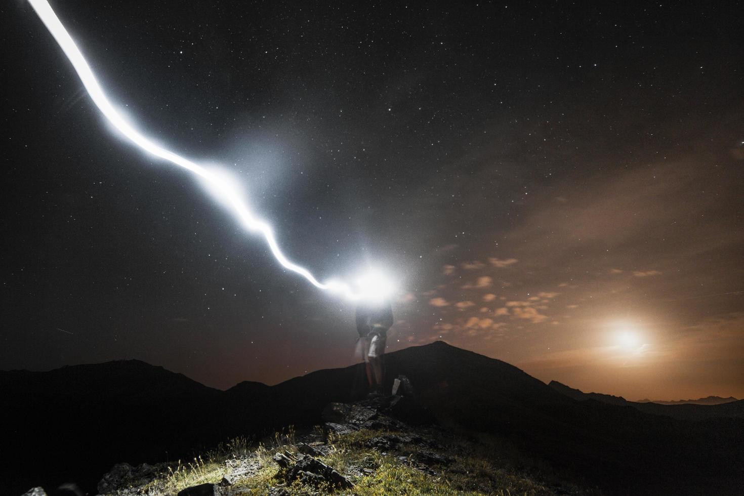 homem parado em um penhasco à noite foto