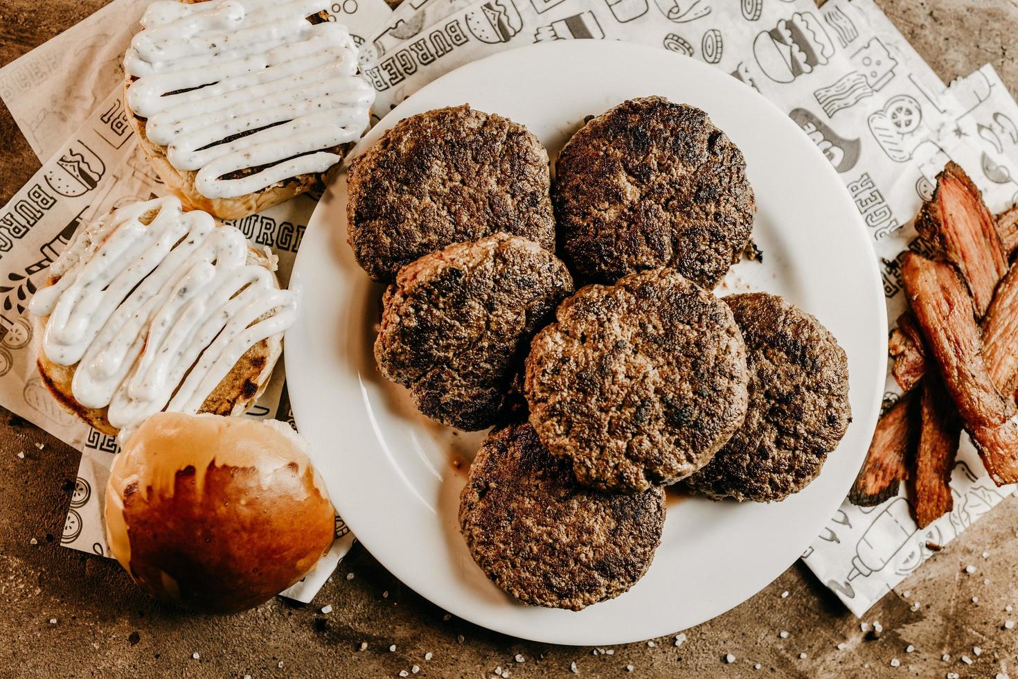 deliciosos hambúrgueres e pãezinhos na mesa foto