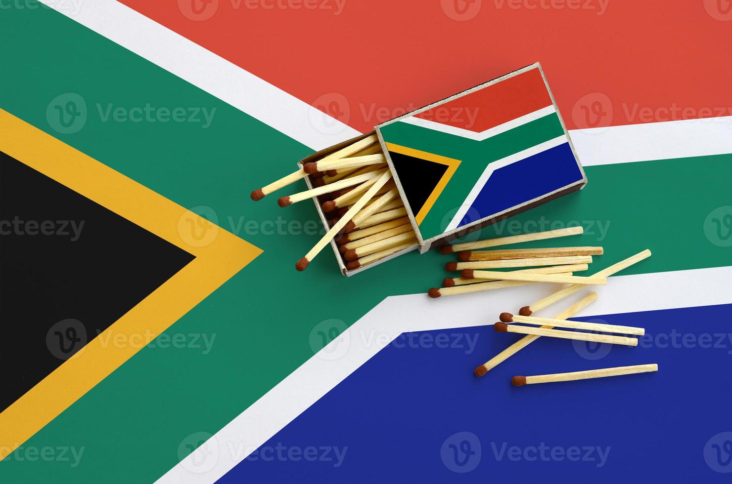 a bandeira da áfrica do sul é mostrada em uma caixa de fósforos aberta, da qual caem vários fósforos e fica em uma grande bandeira foto