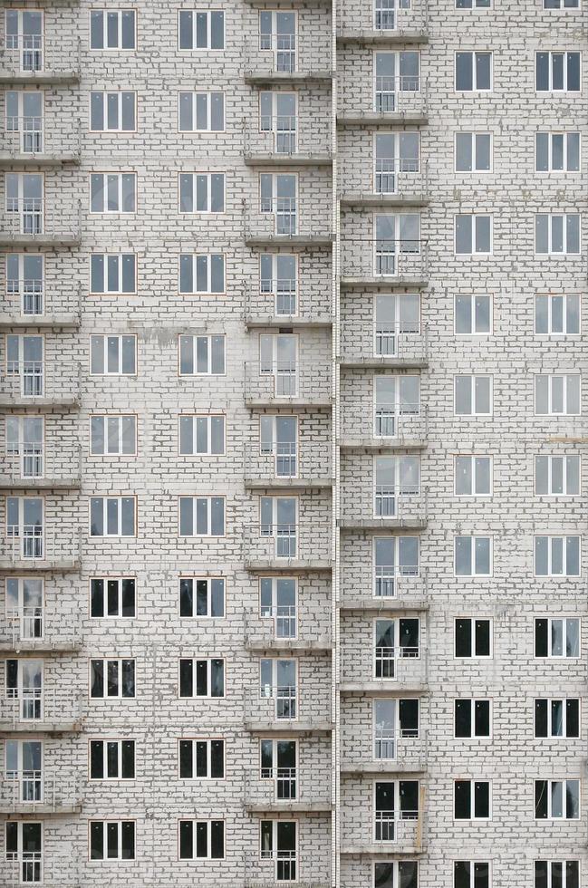 padrão texturizado de uma parede de construção residencial de pedra branca russa com muitas janelas e varanda em construção foto