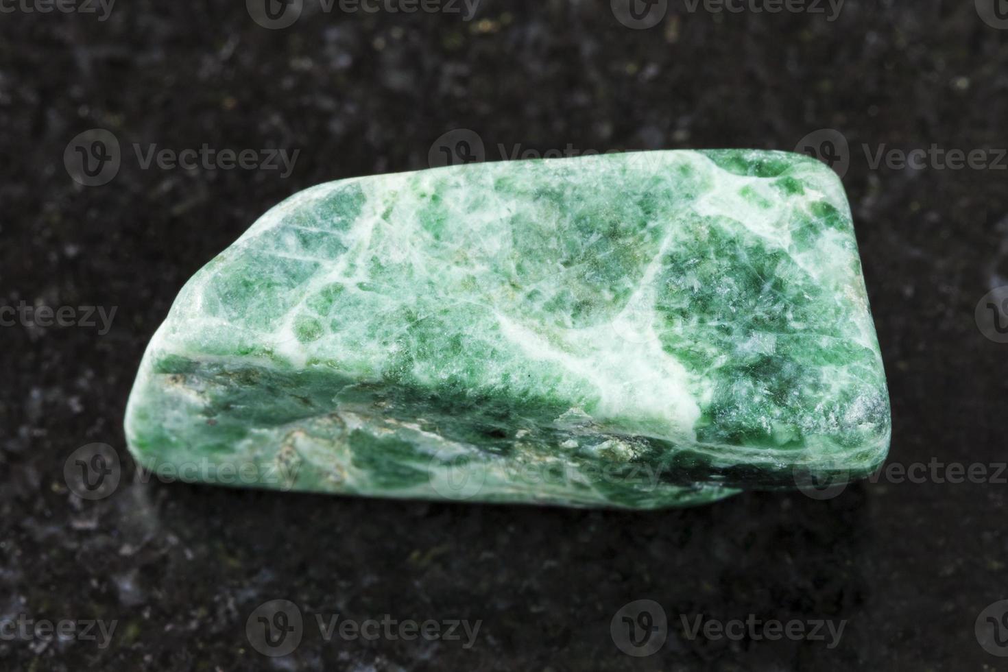 pedra de jadeite verde polida em fundo escuro foto