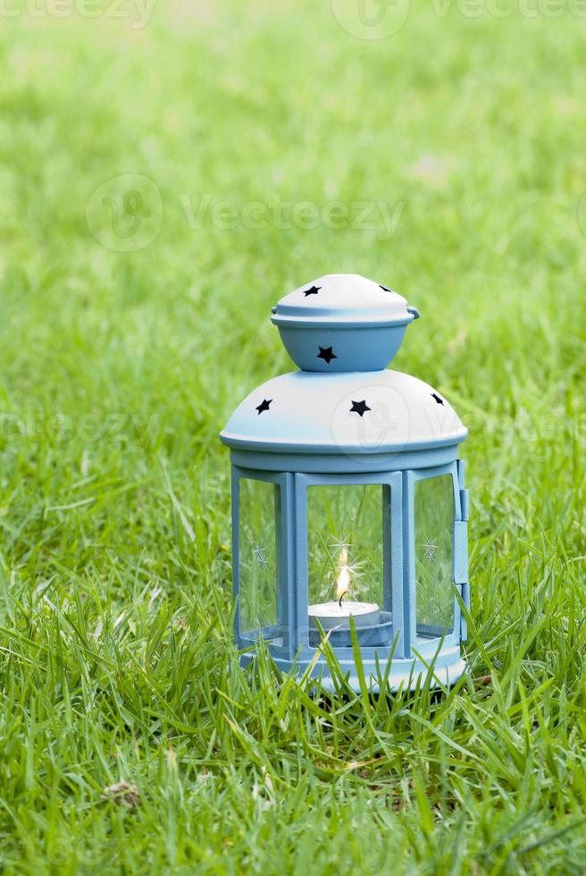 lanterna azul, com uma vela acesa dentro, na grama verde foto
