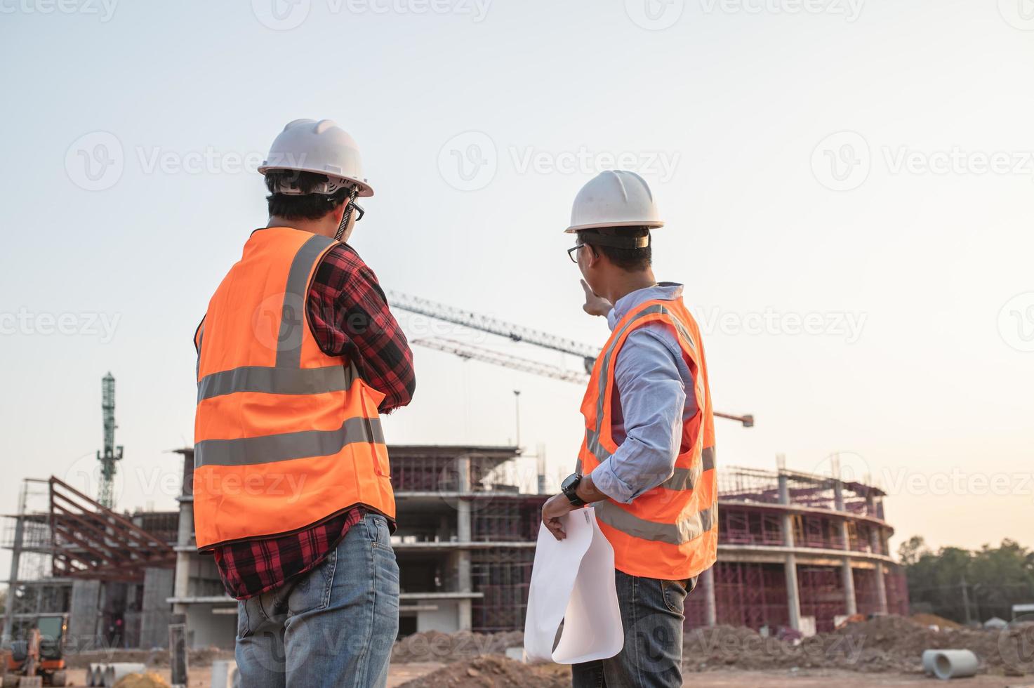 dois engenheiros asiáticos trabalhando no local de um grande projeto de construção, tailândia, trabalham horas extras no canteiro de obras, equipe de engenheiros discus no local foto