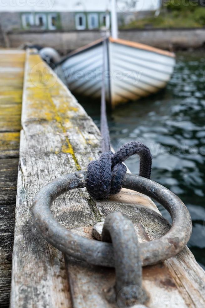 anel de amarração no cais, barco à vela é amarrado com nó no fundo foto