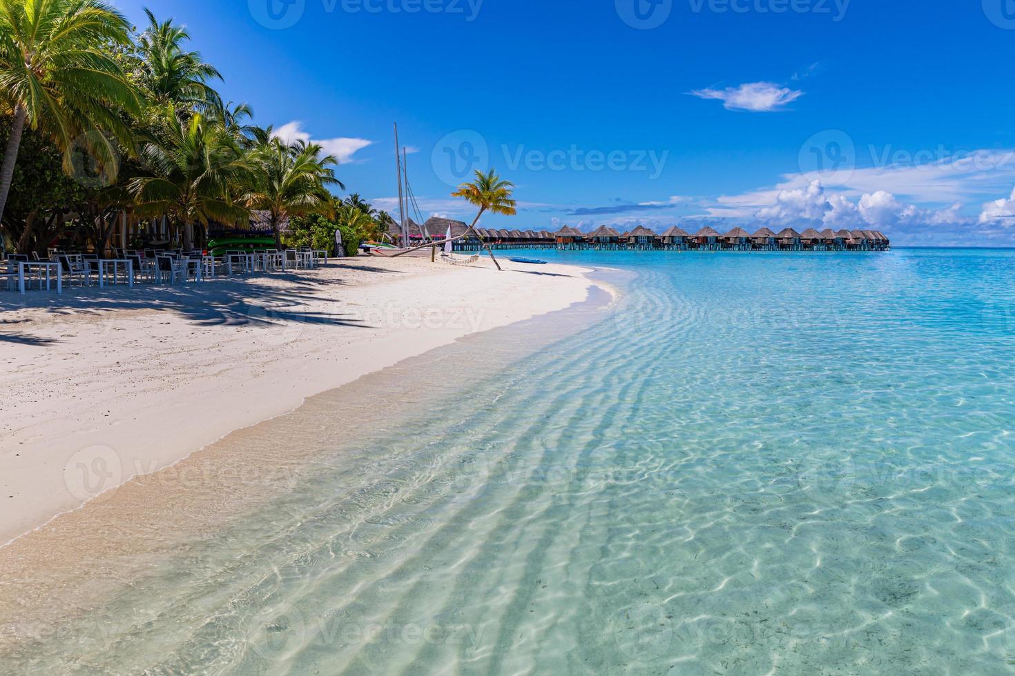 bela praia com areia branca, lagoa do oceano turquesa, palmeiras verdes e céu azul com nuvens em dia ensolarado. paisagem tropical de verão, vista panorâmica. praia tropical nas férias de maldivas foto