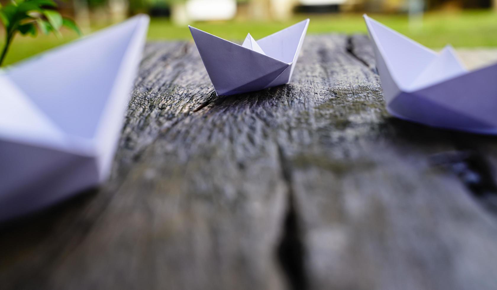 origami, barco de papel branco isolado em um piso de madeira. barquinhos de papel significam andar. sentimento de liberdade liderança foto