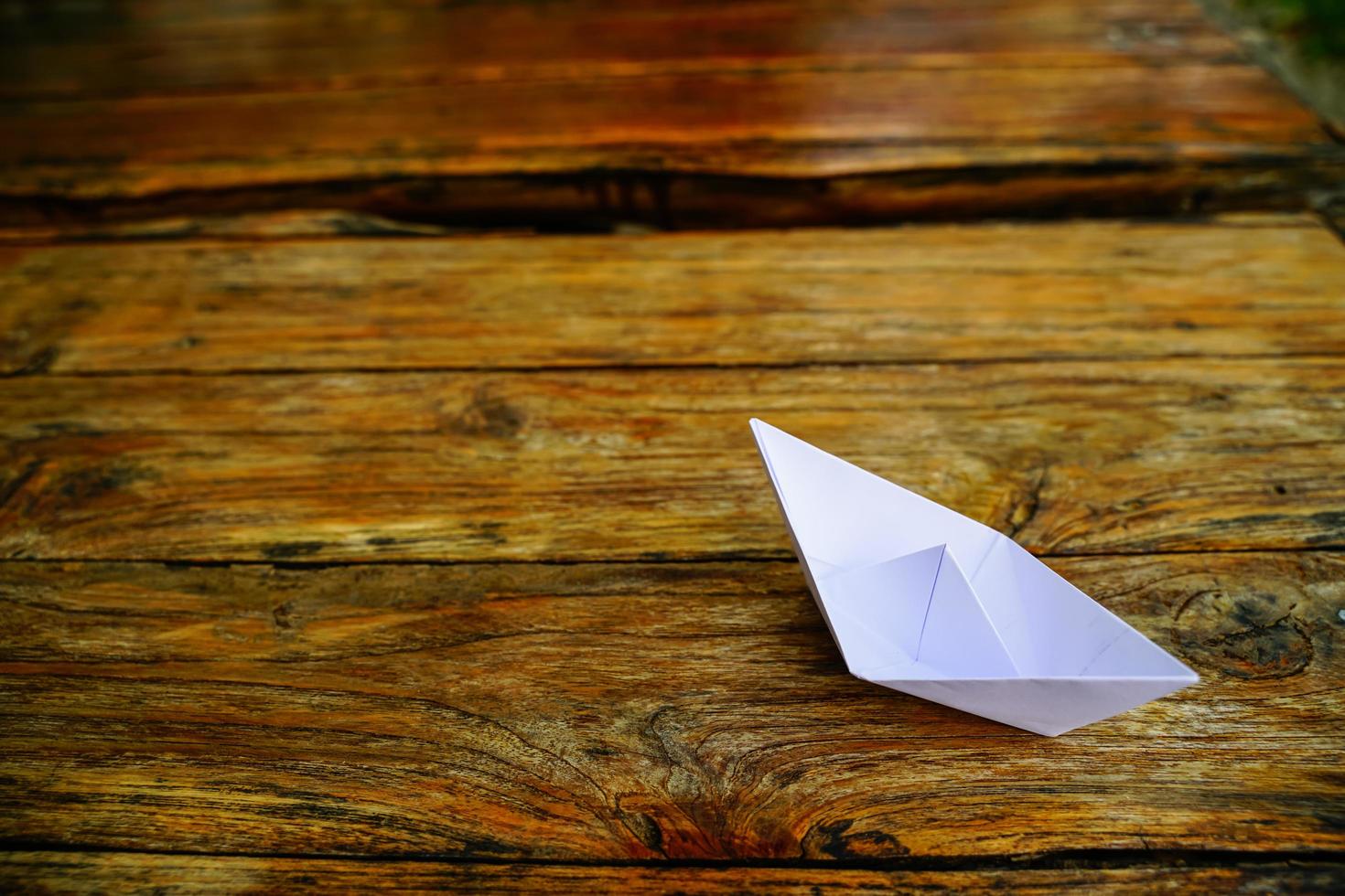 origami, barco de papel branco isolado em um piso de madeira. barquinhos de papel significam andar. sentimento de liberdade liderança foto