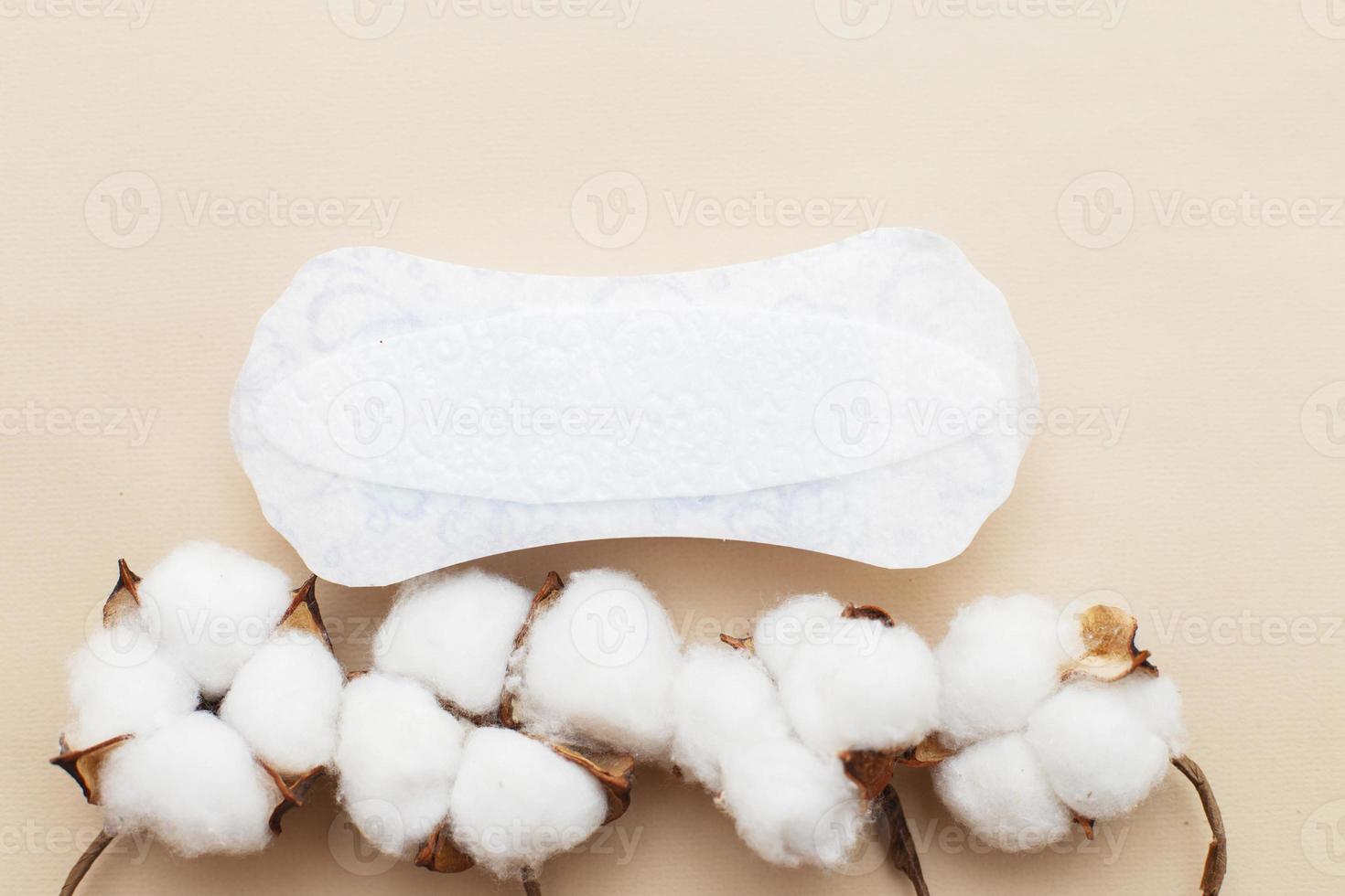 absorvente feminino com uma flor de algodão em fundo bege foto