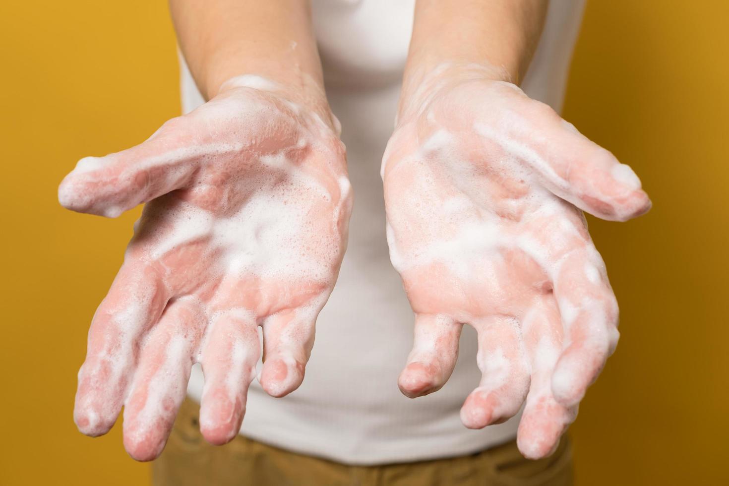 mulher mostra as mãos em espuma de sabão, sobre um fundo amarelo. conceito de uma forma eficaz de prevenir a propagação de infecções. fechar-se. foto