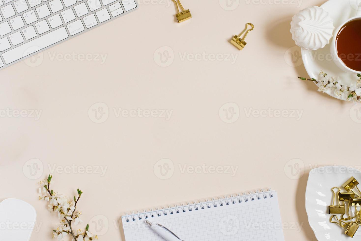 espaço de trabalho do blogueiro de beleza de moda com teclado de laptop, flores de maçã, xícara de chá, marshmallow em fundo bege. configuração plana, vista superior, espaço de cópia foto