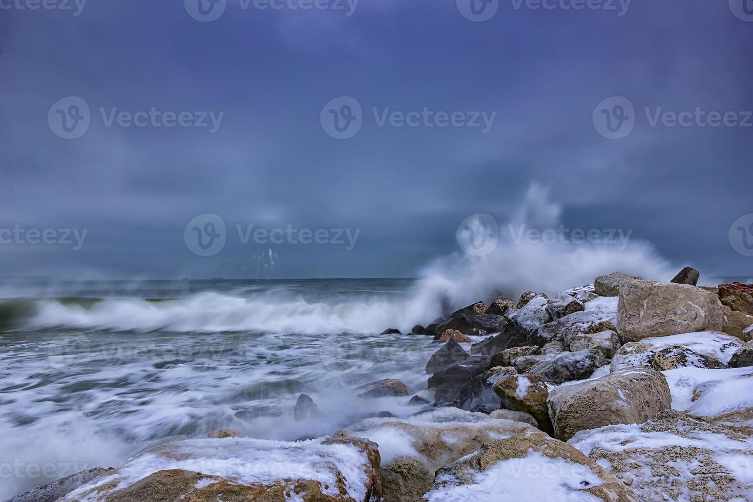 onda de inverno do mar atinge o quebra-mar. nuvens de tempestade foto