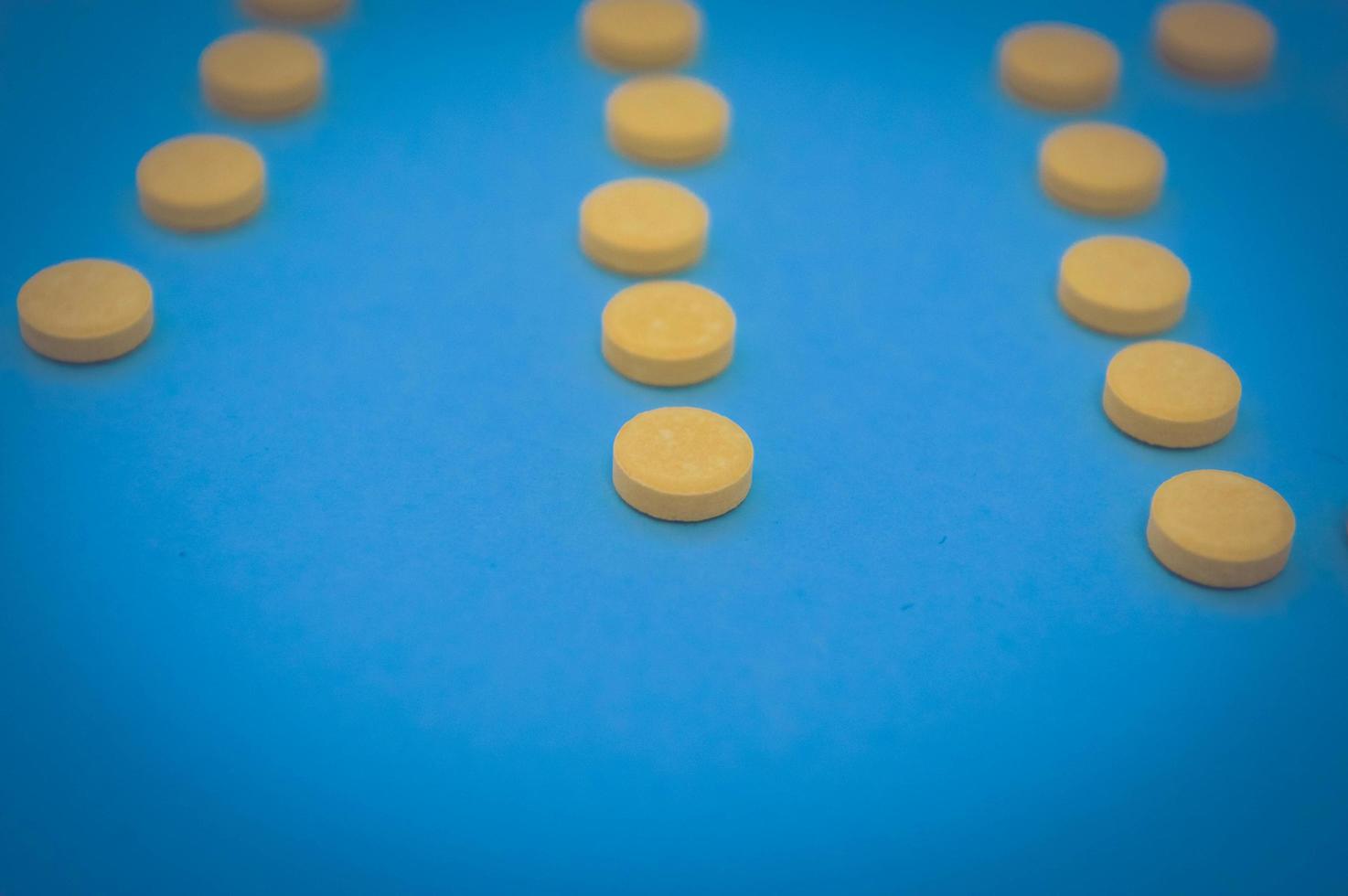farmacêutico médico redondo amarelo para o tratamento de doenças e a morte de micróbios e vírus pílulas e vitaminas medicamentos para coronavírus em um fundo azul foto