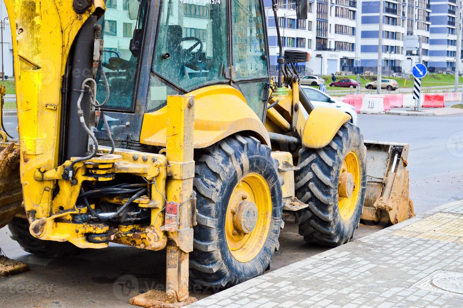 grande trator de escavadeira pesada industrial amarelo brilhante, bulldozer, equipamento de construção especializado para reparo de estradas durante a construção de um novo microdistrito em uma cidade grande foto