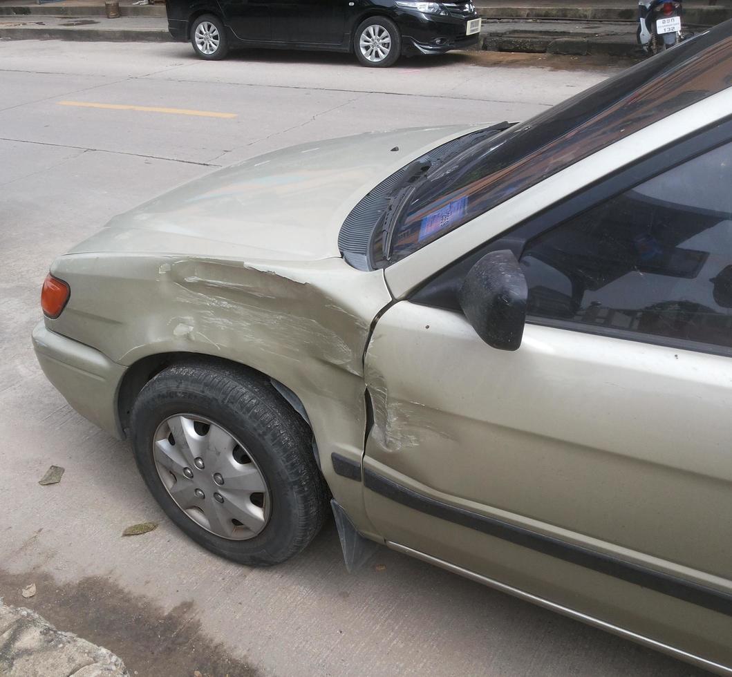 amassado do carro de cor dourada ao lado da roda esquerda de um acidente. foto