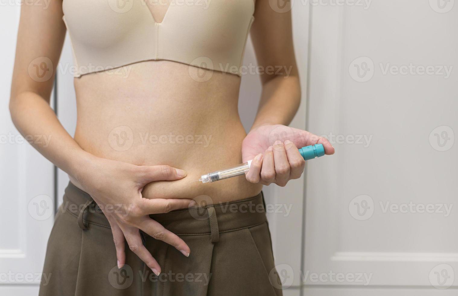 Feche a mulher usando injeção de tratamento de fertilização in vitro na barriga para preparar a fertilidade reprodutiva, estimulação da ovulação. foto