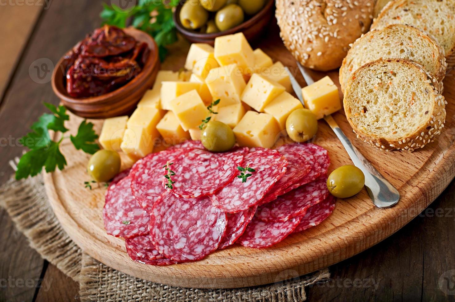 prato de antepasto com salame e queijo em um fundo de madeira foto