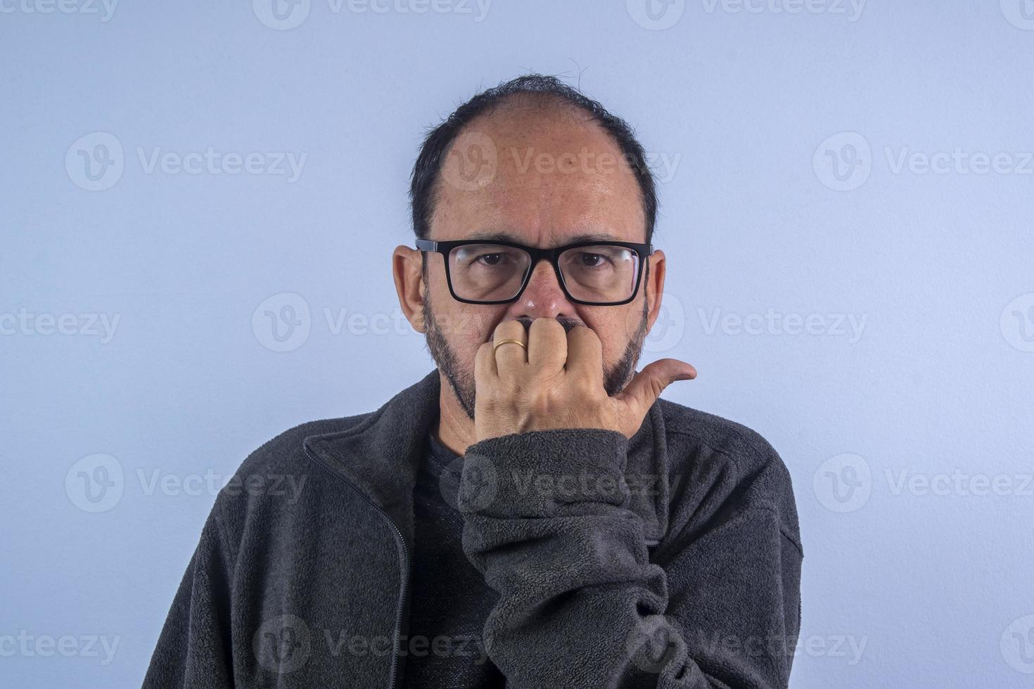 retrato de homem barbudo de 60 anos sobre fundo azul com chapéu e óculos foto