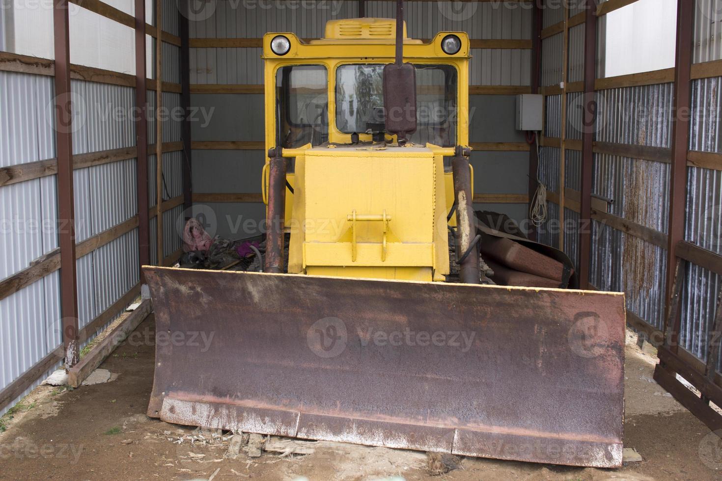 trator de rodas grande com lâmina de trator para limpar estradas da neve. carregadeira de rodas amarela na garagem. foto