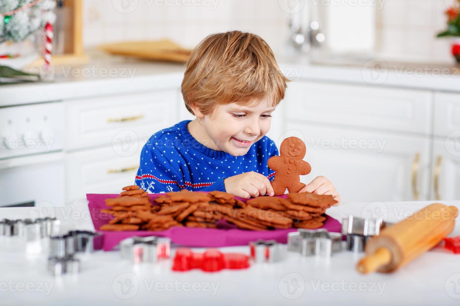 garotinho fazendo biscoitos de gengibre na cozinha doméstica foto