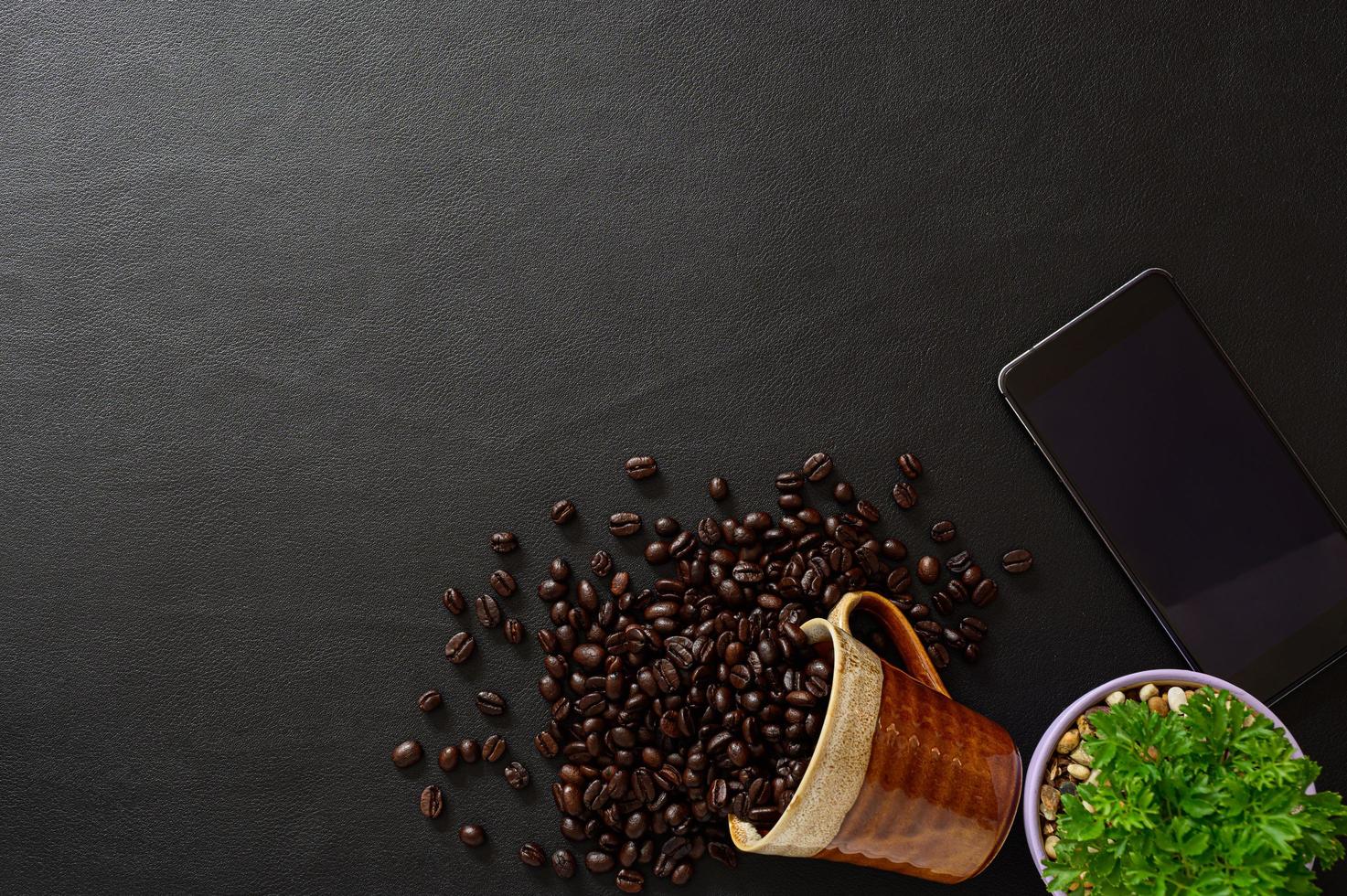 grãos de café e smartphone na mesa foto
