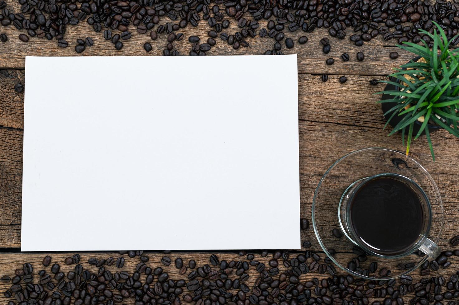 papel em branco e grãos de café na mesa foto