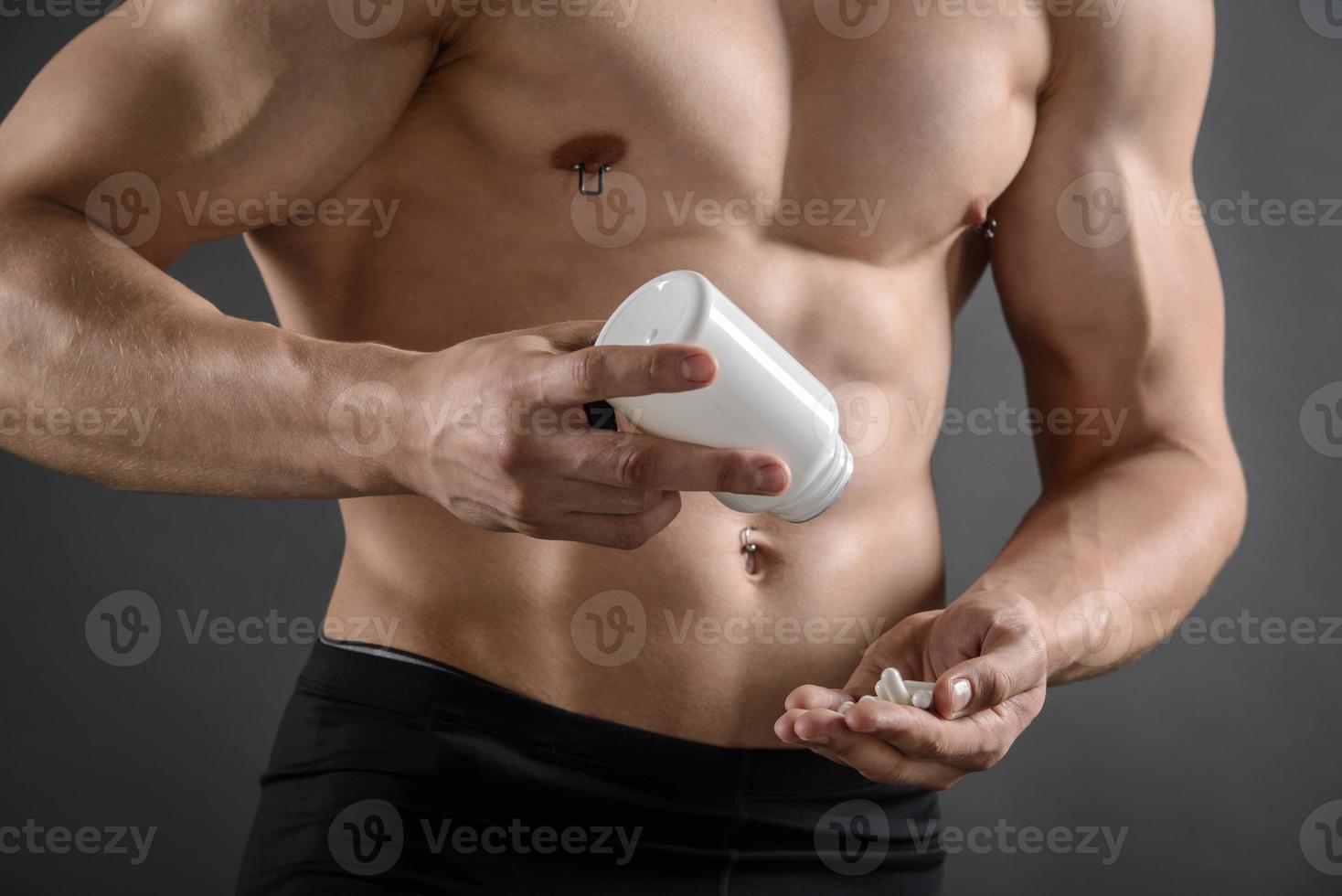 homem musculoso tomando suas pílulas de suplemento foto