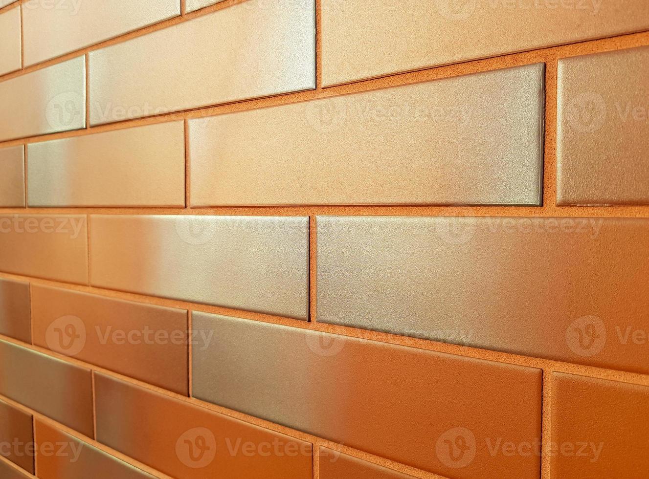 fachada moderna feita de azulejos de cerâmica laranja. tijolos alaranjados brilhantes de parede nova com um tom cinza prateado, brilhando ao sol. perspectiva horizontal recuando na distância. espaço de cópia de fundo. foto