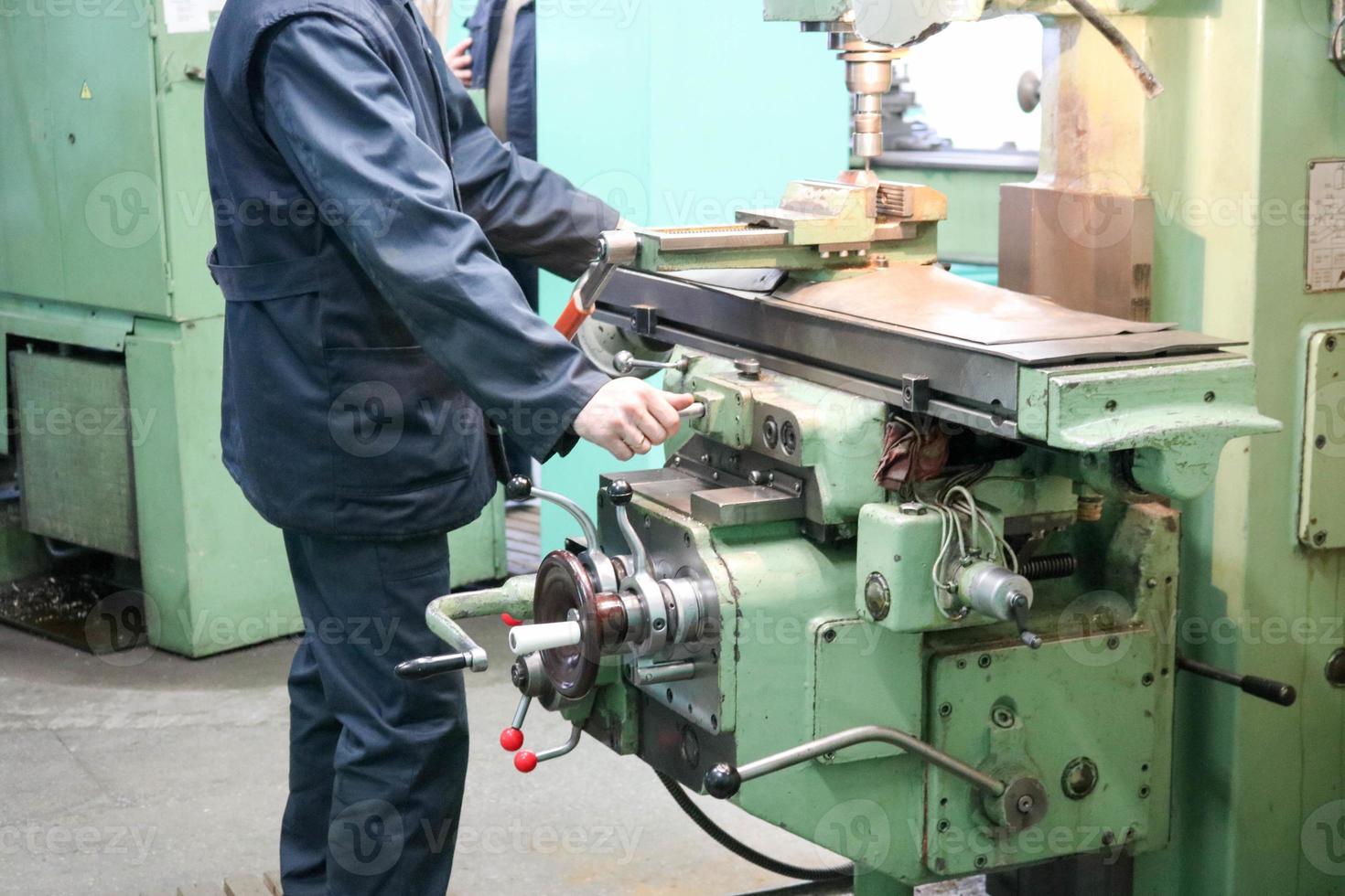 um trabalhador do sexo masculino trabalha em um torno de serralheiro de ferro de metal maior, equipamento para reparos, trabalho em metal em uma oficina em uma planta metalúrgica em uma produção de reparo foto