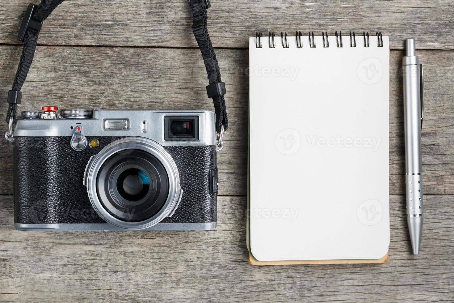 câmera clássica com página de bloco de notas em branco e caneta cinza na mesa vintage de madeira cinza foto