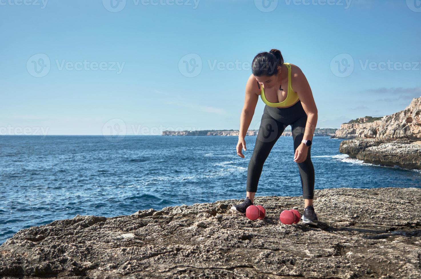 mulher latina fitness em esportes conjunto treinamento com elástico, pesos, exercícios de ginástica, em frente à água. foto