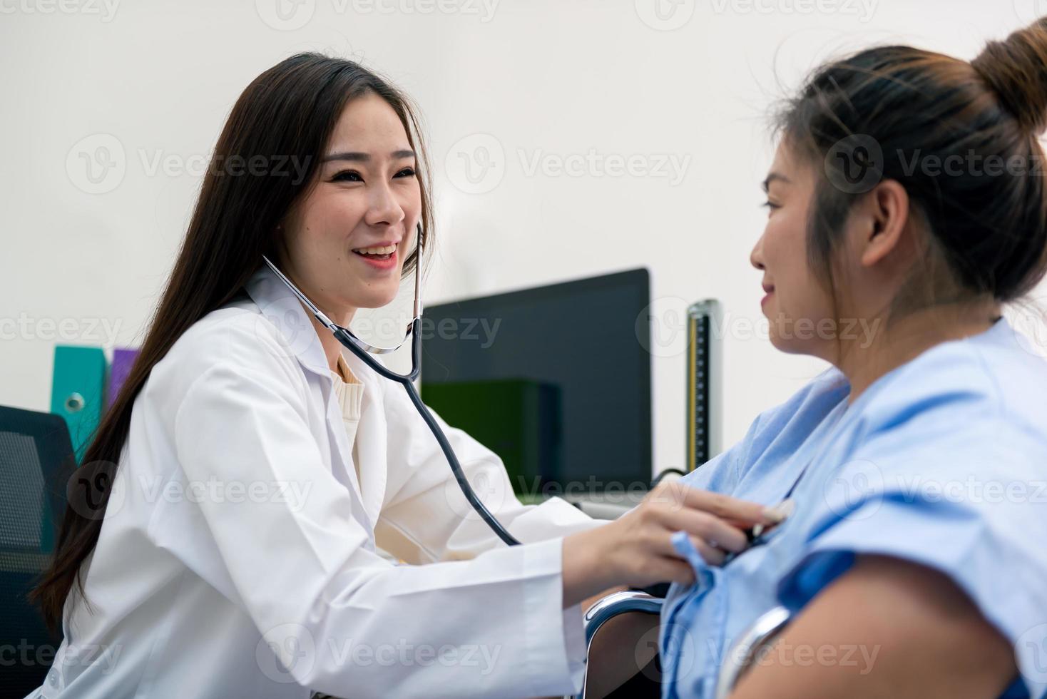 cardiologista médica asiática examinando mulher gorda cardíaca paciente ouvindo verificando batimentos cardíacos usando estetoscópio. foto