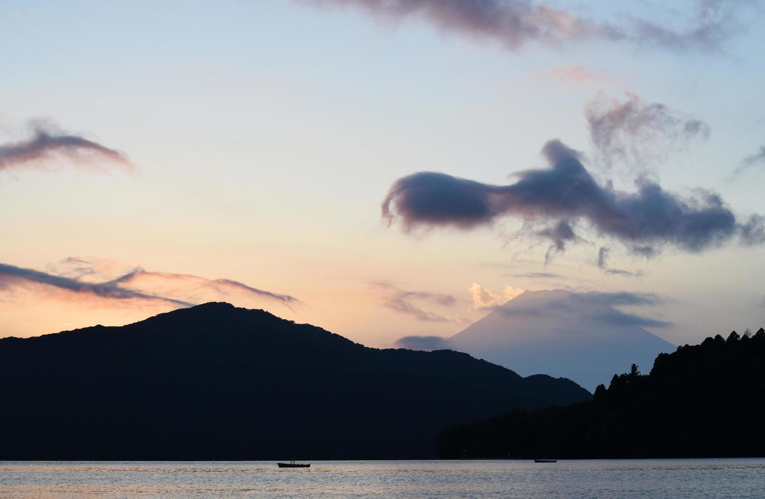 água em silhueta e montanhas durante o pôr do sol foto