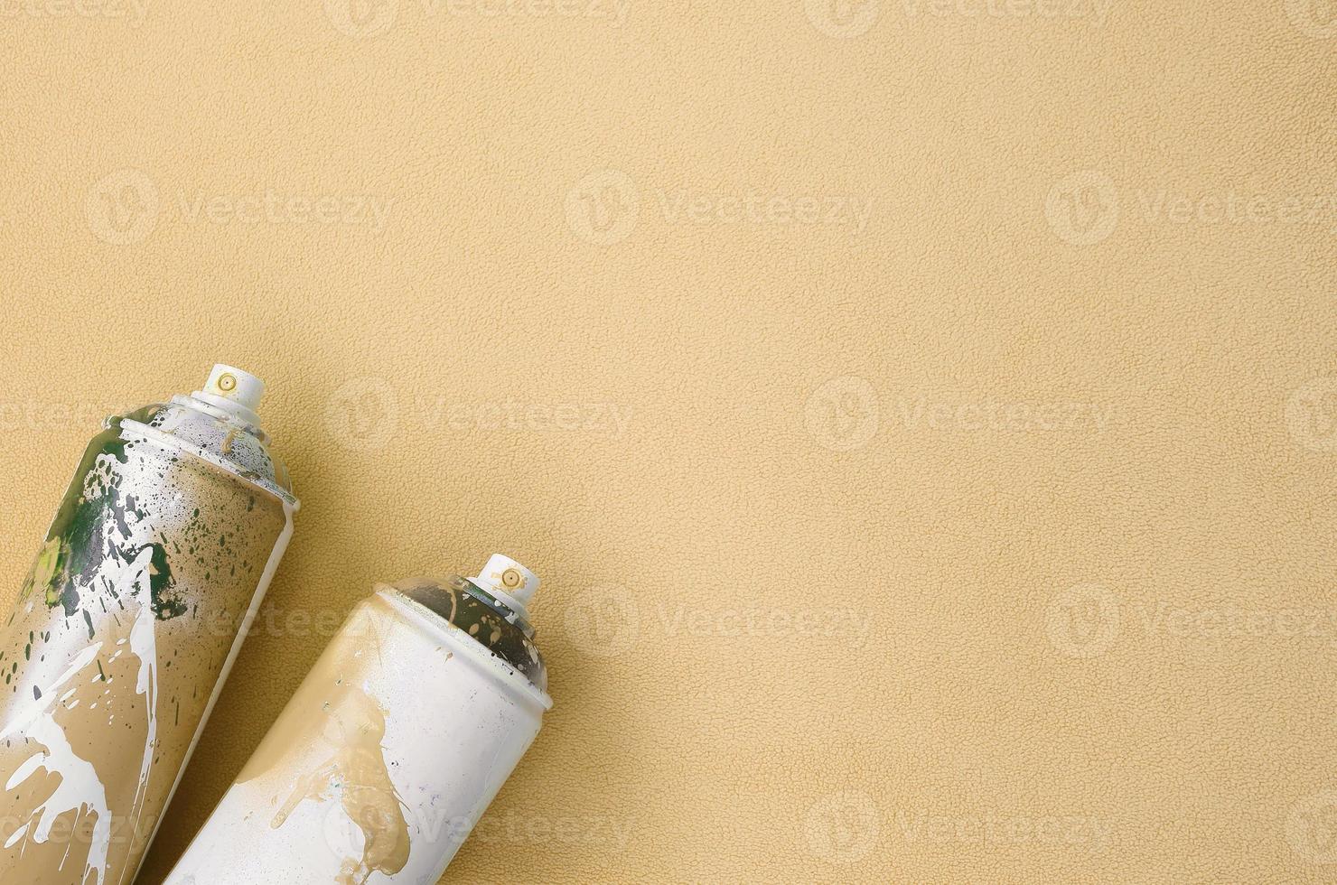 algumas latas de spray de aerossol laranja usadas com gotas de tinta estão em um cobertor de tecido de lã laranja claro macio e peludo. cor de design de moda clássica. conceito de vandalismo de graffiti foto