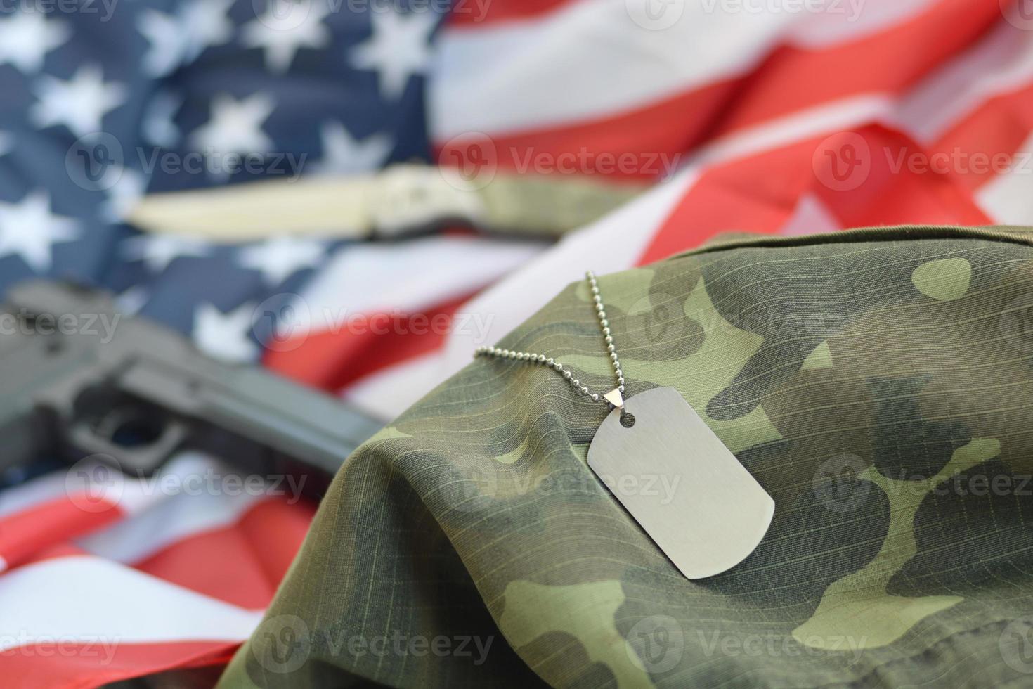 token de etiqueta de cão do exército com balas de 9 mm e pistola deitada na bandeira dos estados unidos dobrada e uniforme de camuflagem foto