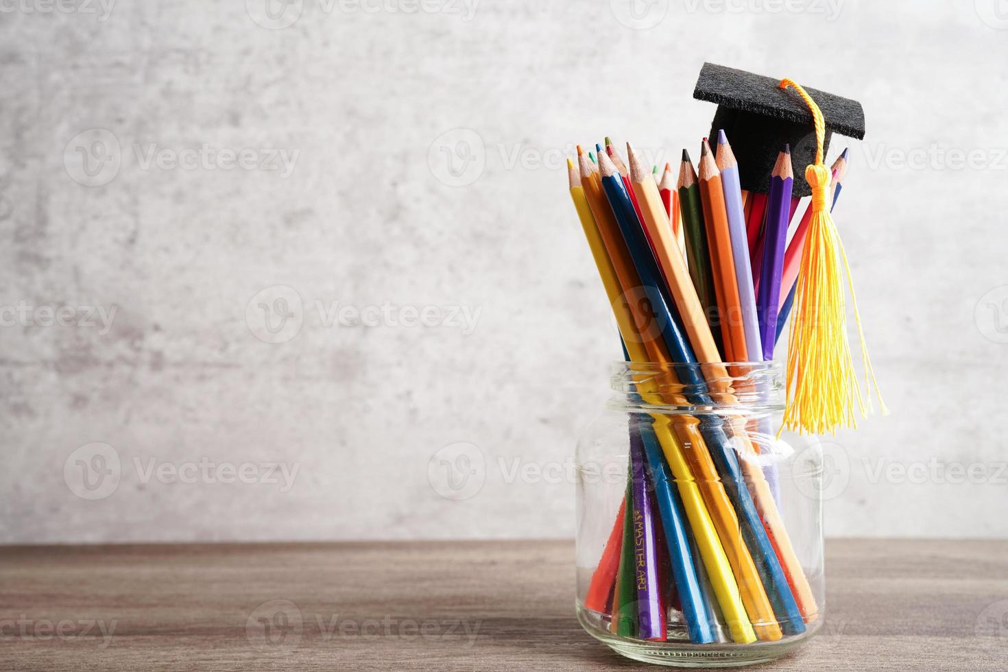 chapéu de formatura com lápis coloridos no livro com espaço de cópia, aprendendo o conceito de educação universitária. foto