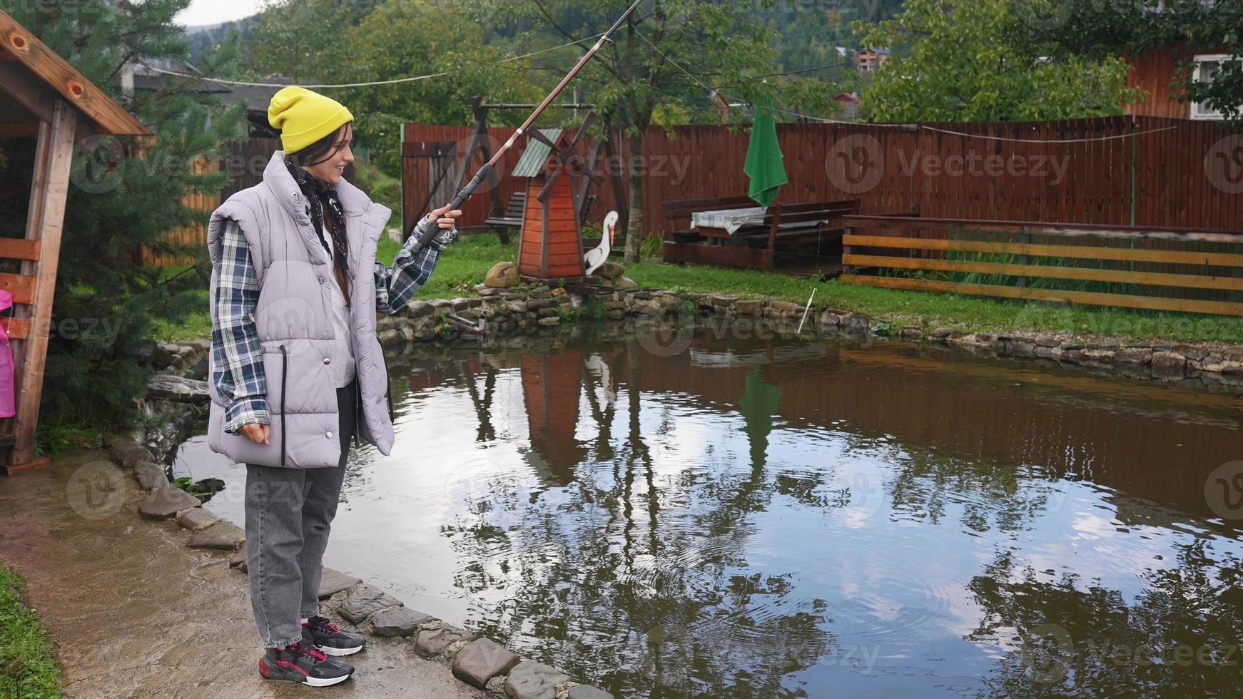 jovem mulher bonita está pescando em um pequeno lago foto