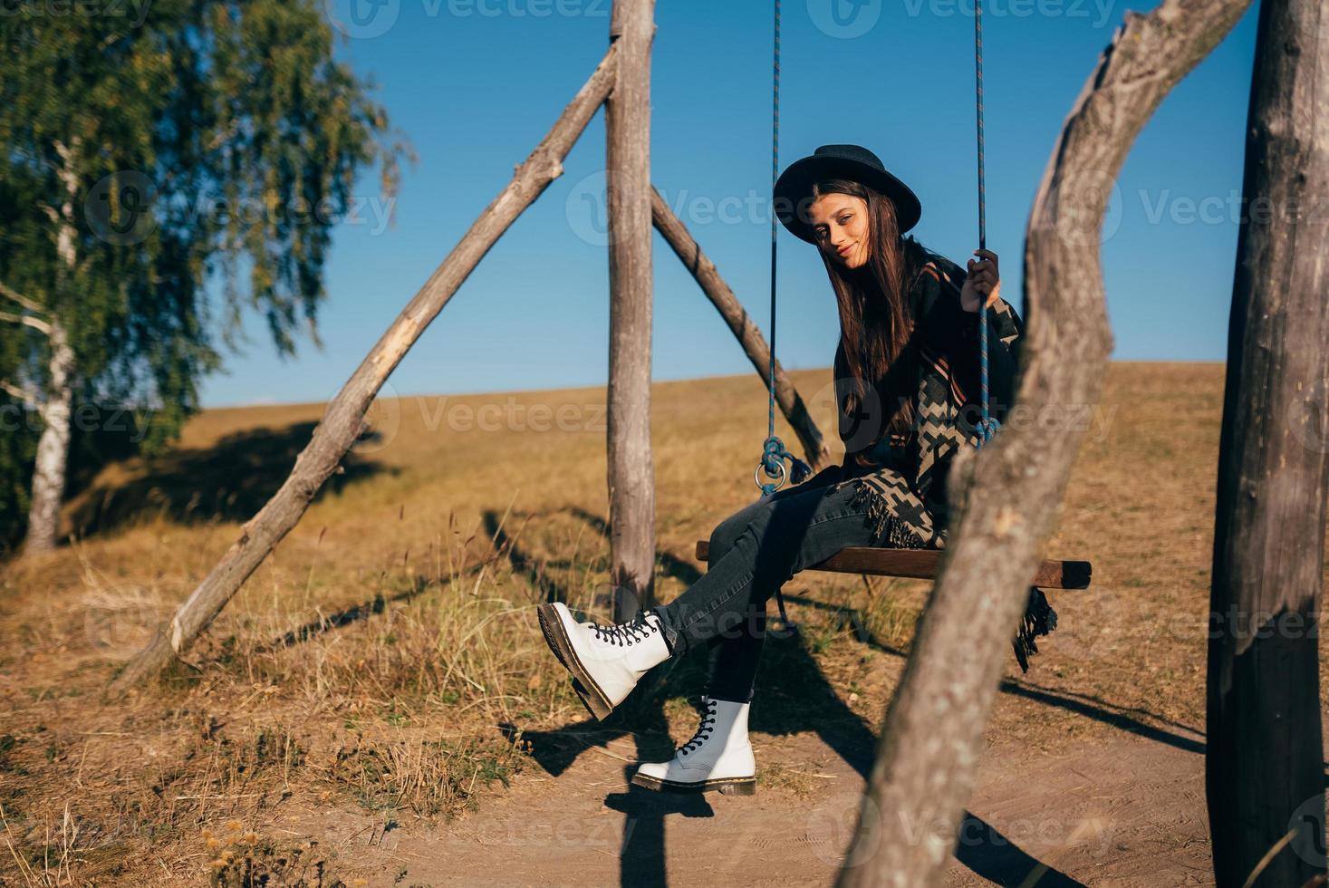 jovem mulher bonita anda em um balanço no campo foto