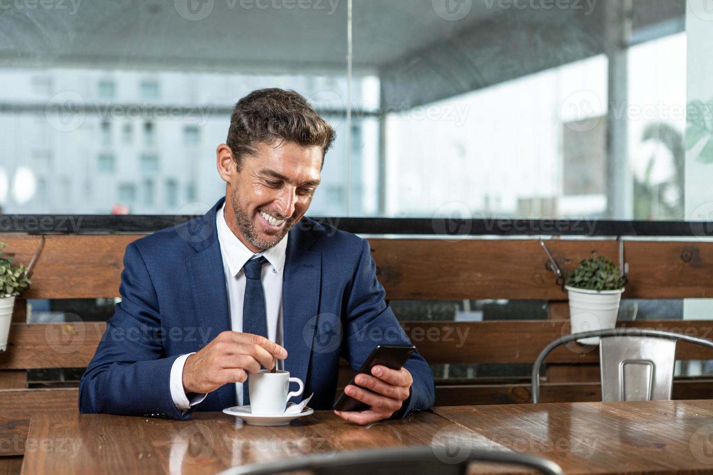 executivo masculino alegre navegando no celular no refeitório foto