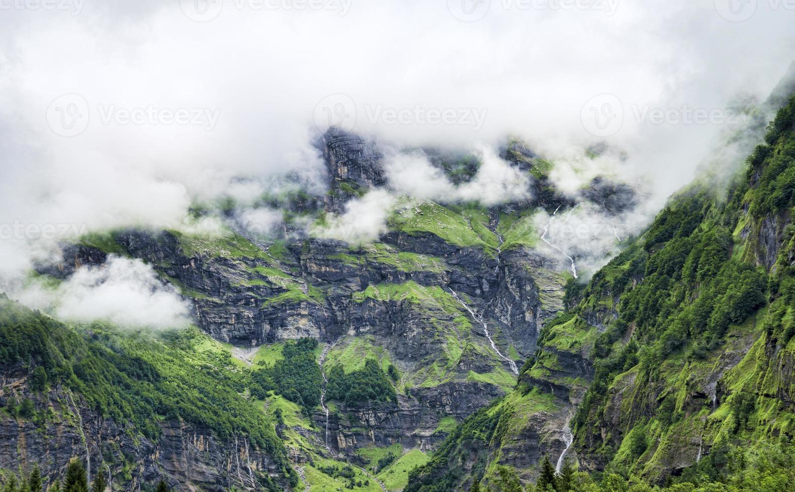 paisagem alpina com cicatrizes cobertas de musgo e cachoeiras entre nuvens baixas foto