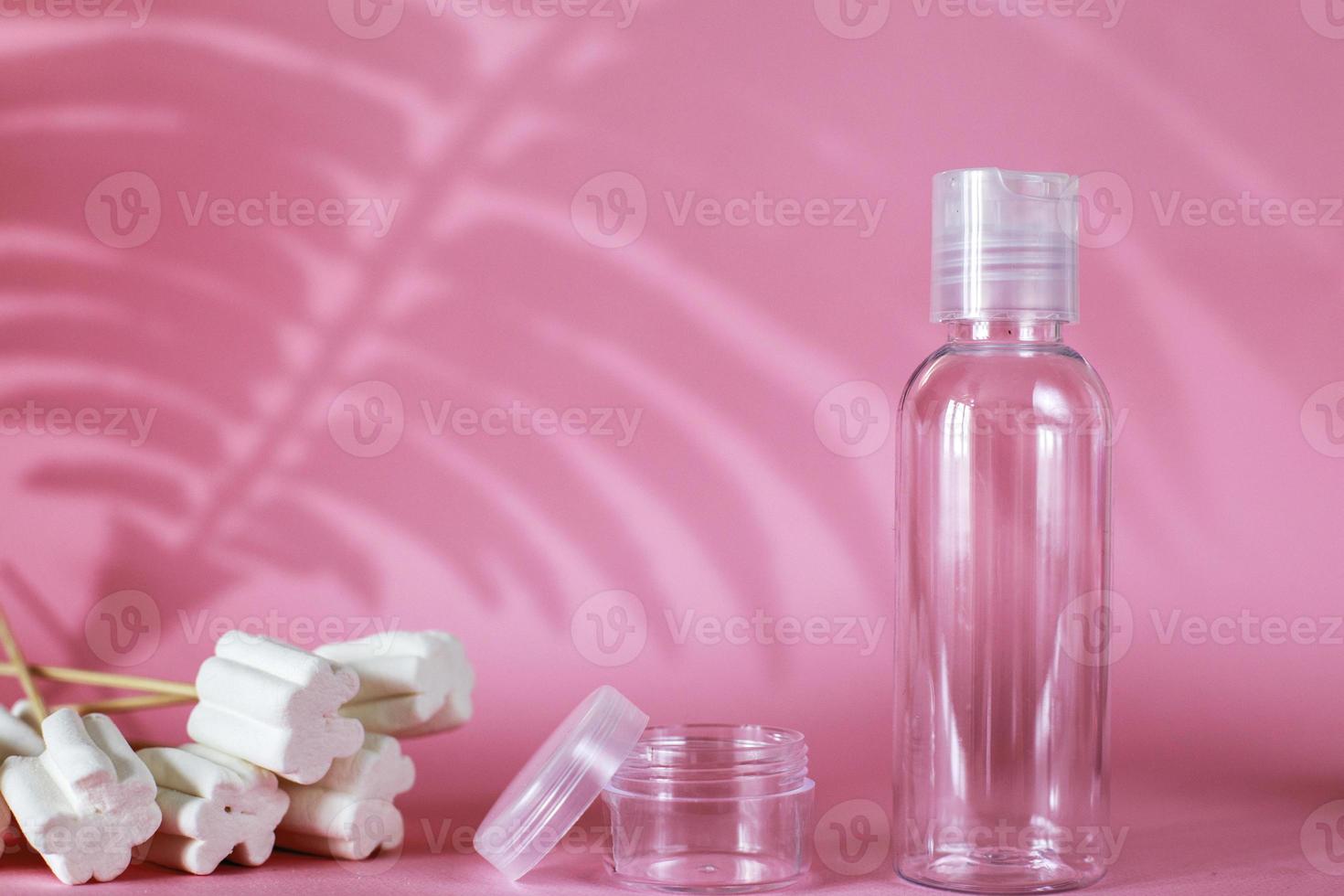 produtos cosméticos de spa com doces, tubo vazio transparente no fundo rosa. garrafa para agente de limpeza detergente foto