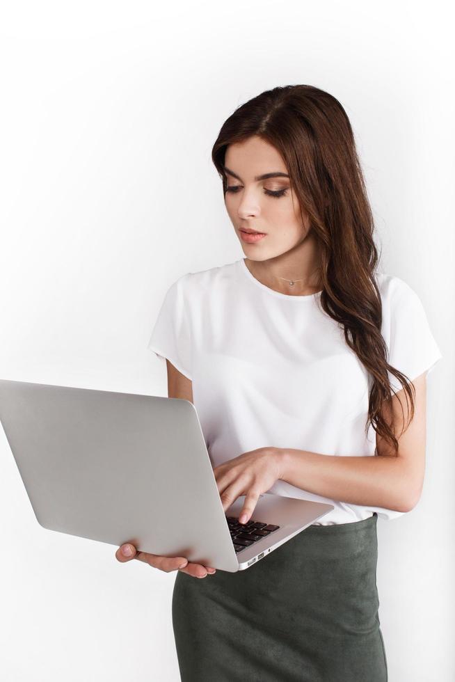 mulher vestida com estilo empresarial trabalha em laptop em fundo branco foto