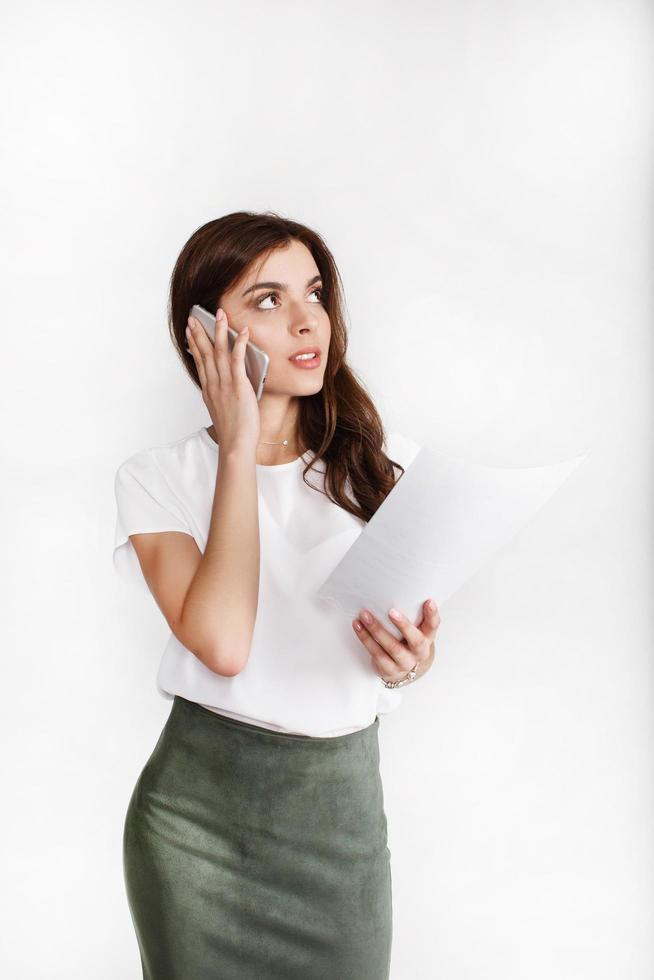 mulher vestida com estilo de escritório fala ao telefone sobre a papelada foto