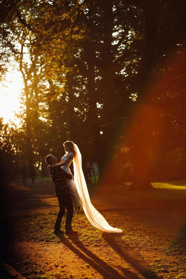 lindo casal de noivos se abraçando no parque com halos de sol foto