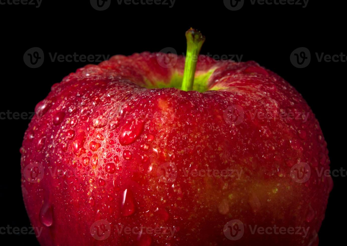 gota de água na superfície brilhante de maçã vermelha em fundo preto foto