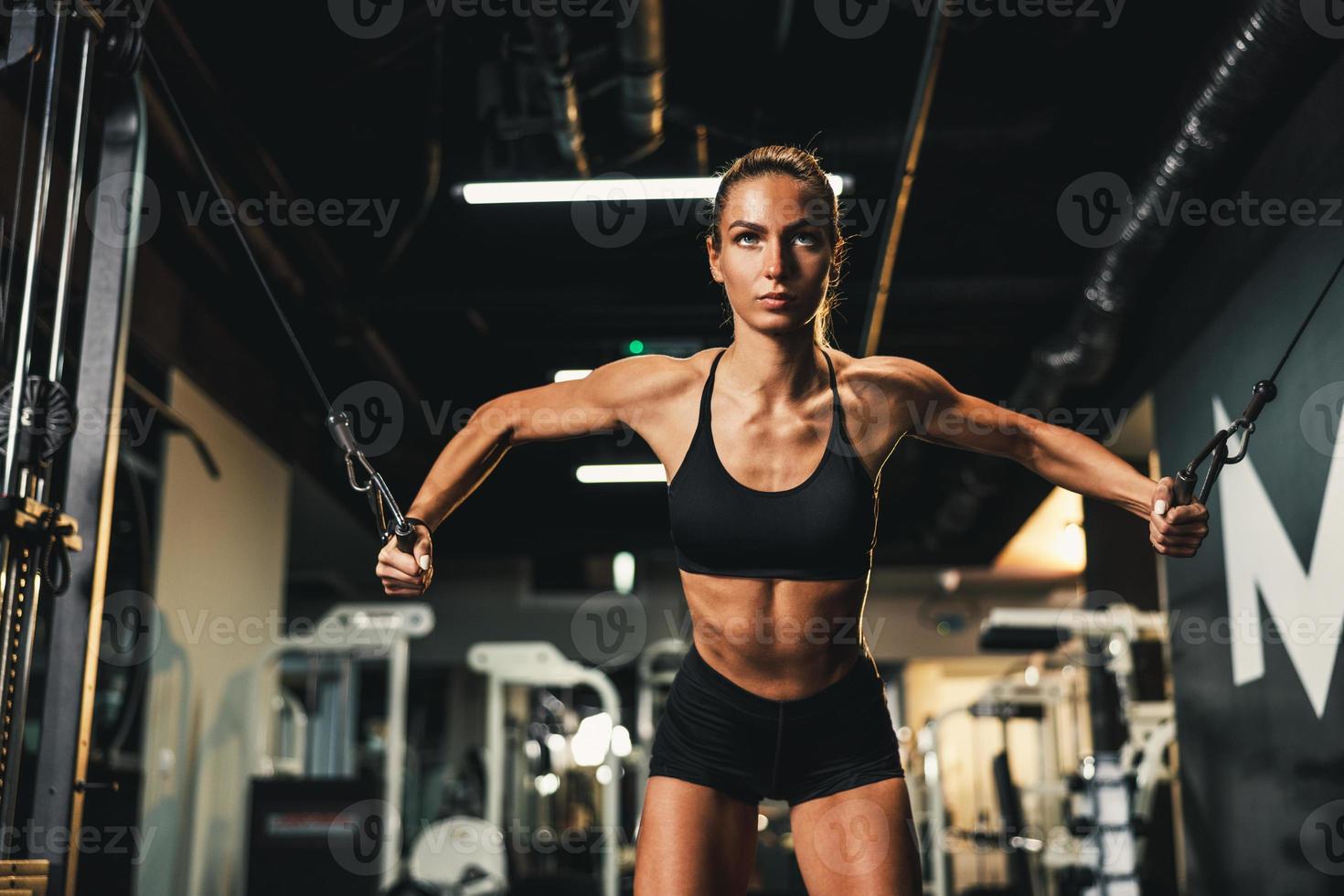 mulher fazendo treinamento na máquina para o músculo do peito na academia foto