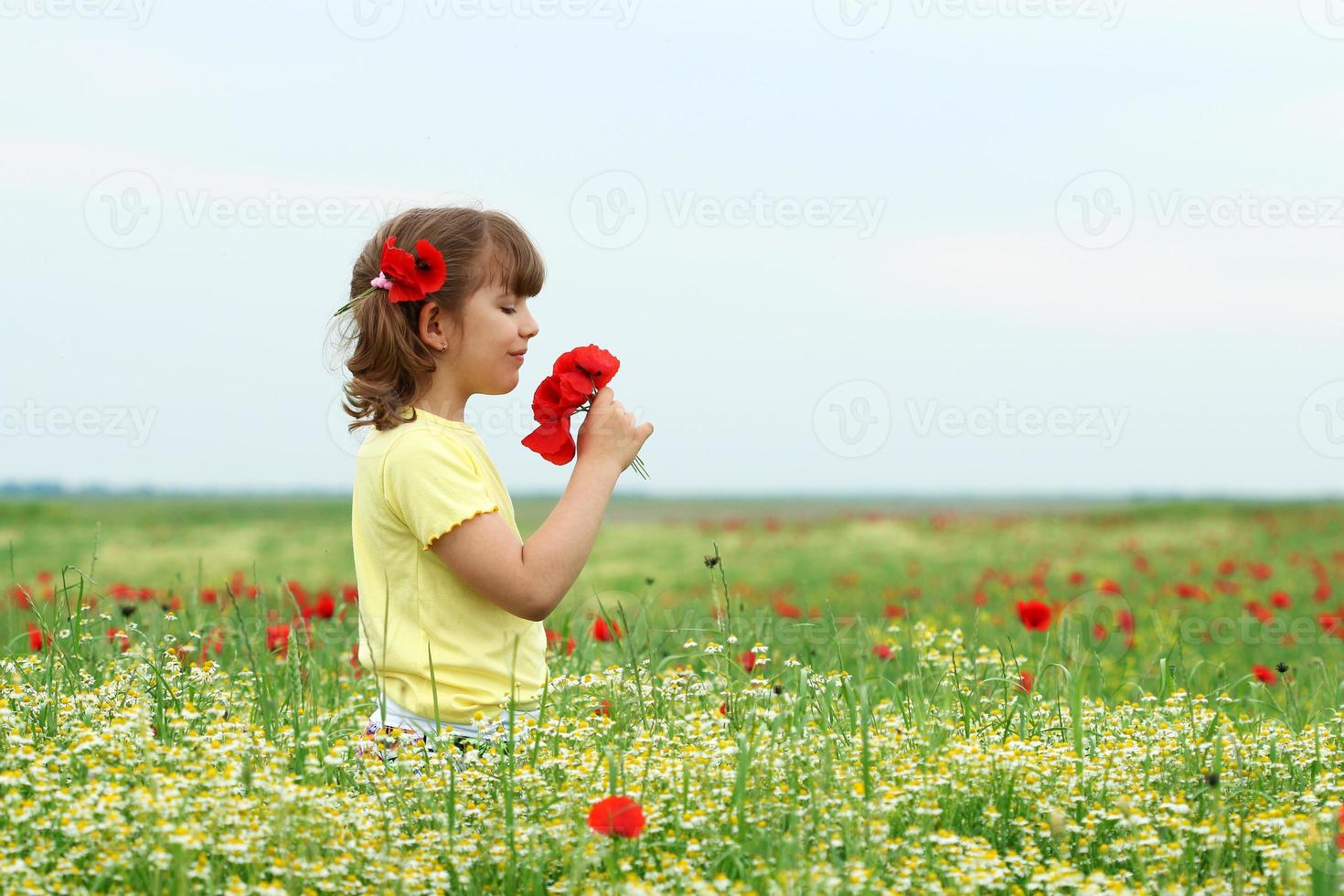 linda garotinha com flores de papoula na primavera foto